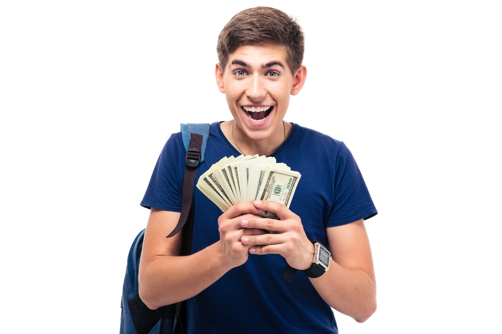 Cheerful male student holding money isolated on a white background. Looking at camera