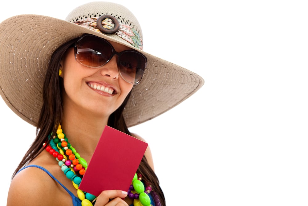 Woman ready to travel wearing a hat and holding her passport - isolated